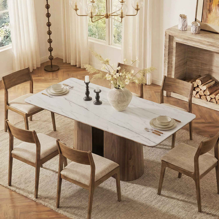 Dining room with marble table and wooden chairs in a well-lit room.