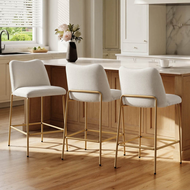 White upholstered barstools with gold metal bases at a kitchen island
