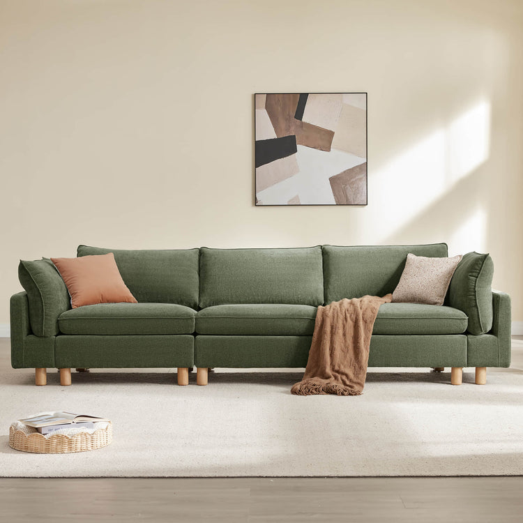 Green modular 3-seat sofa with wood legs, plush cushions, decorative pillows, and throw blanket.
