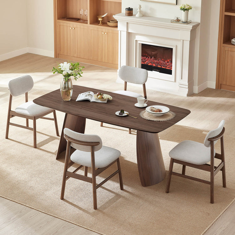 Dining room with a wooden table and chairs in front of a fireplace.