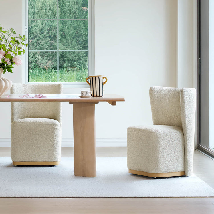Two cream textured wingback chairs at a wooden dining table in a bright modern room - CHITA Living