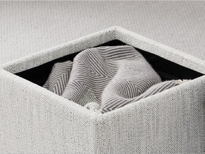 White cube ottoman with gray blanket inside on textured rug, ideal for modern living spaces - CHITA Living