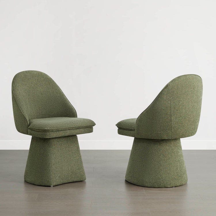 Two green swivel chairs on a wooden floor against a white wall.