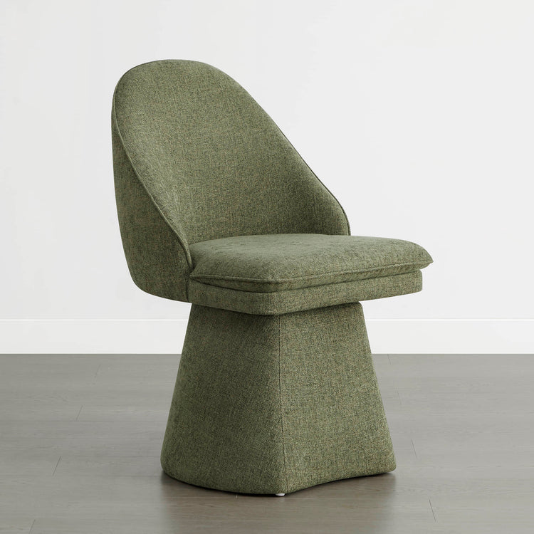 A single green swivel chair angled slightly to the side on a wooden floor against a white wall.