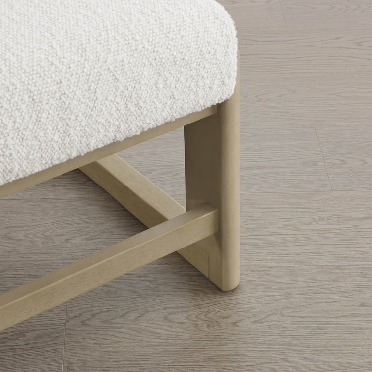 The Troy Boucle Dining Chair features a creamy bouclé seat cushion and sturdy, light-colored solid wood legs.