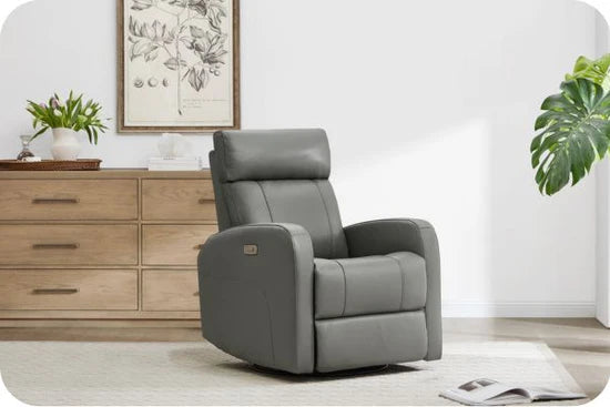 A modern gray recliner in a living room with a wooden cabinet and a plant in the background.