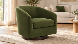 Forest-green Wren accent chair with a dark wood base beside a cream sofa in a bright living room