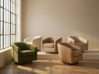 Five barrel-back swivel accent chairs in green velvet, cream boucle, white textured fabric, brown boucle, and tan leather, arranged on a wood floor in a sunlit minimalist room with large windows.