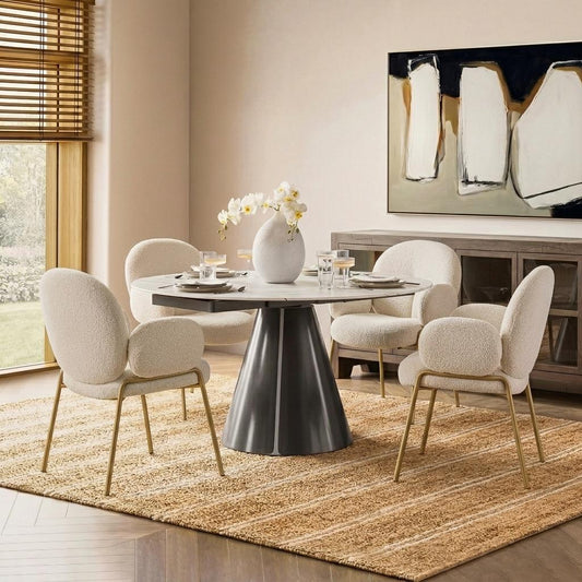 Round marble dining table with a dark conical base and four cream bouclé chairs.
