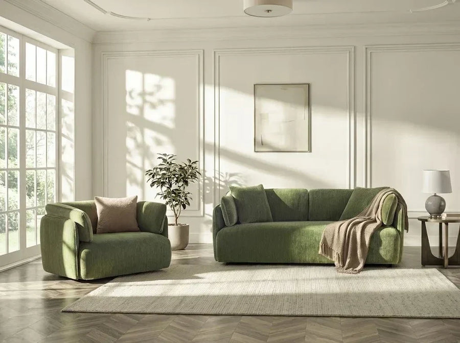 Green armchair and sofa on a rug in a sunlit living room with a large window.