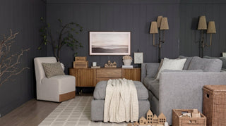 A beautifully styled kids' playroom featuring a light gray Delaney modular sofa, a storage ottoman, a wooden console, and a comfortable Aida chair against a dark gray accent wall.