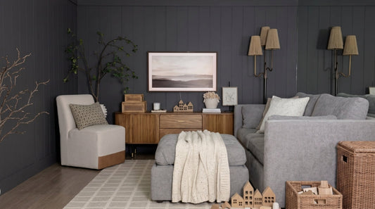 A beautifully styled kids' playroom featuring a light gray Delaney modular sofa, a storage ottoman, a wooden console, and a comfortable Aida chair against a dark gray accent wall.