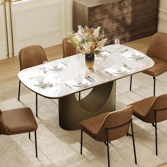 Soft-corner marble dining table with brown chairs, floral centerpiece, white place settings, and wood storage in a warm modern dining room.