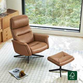 Brown leather lounge chair and matching ottoman beside a forest-view window, patterned rug, wood cabinet, and FSC certification badge nearby.