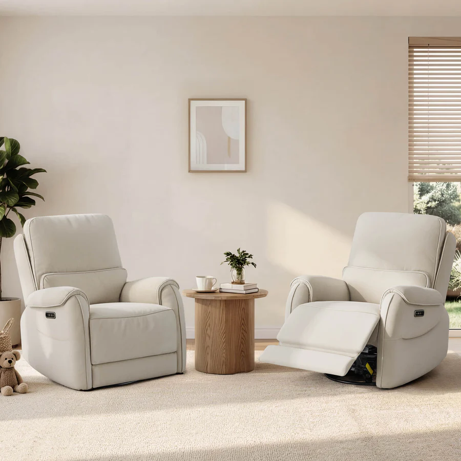 Two cream power recliners sit beside a small wooden table in a bright neutral bedroom-style space, with one chair fully upright and the other extended.