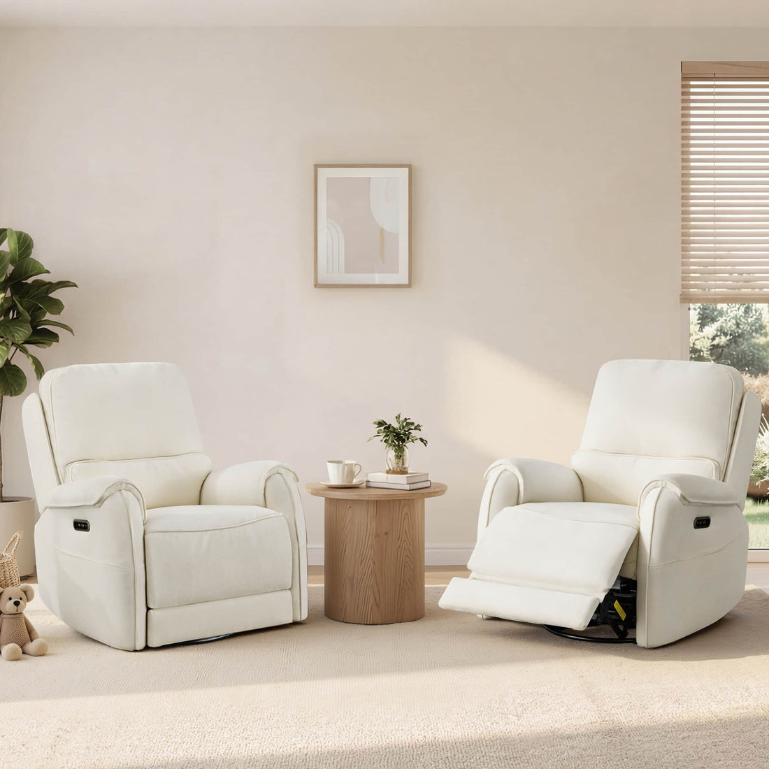 Two ivory power recliners sit beside a round wood table in a sunlit living room with plants, blinds, and soft neutral decor.