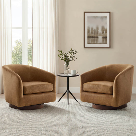 Two caramel brown barrel lounge chairs sit beside a small black table in a bright neutral room with soft curtains.