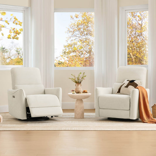 Two cream recliner chairs sit beside a round table in a bright living room with large windows and autumn trees outside.