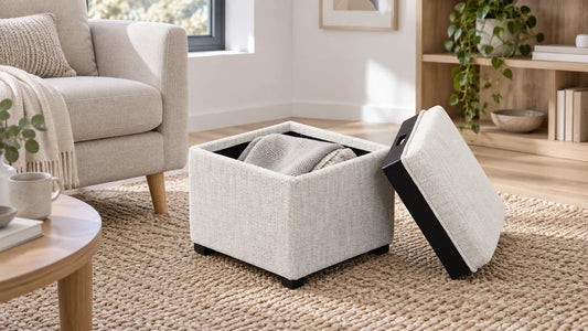 Open cream storage ottoman with its removable lid leaning beside it and a folded blanket inside.