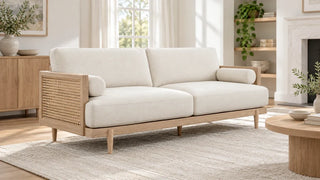 Cream upholstered sofa with a wooden frame and a woven cane side panel in a bright indoor room.