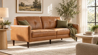 Caramel leather sofa with olive cushions, cream curtains, and an ivory rug.