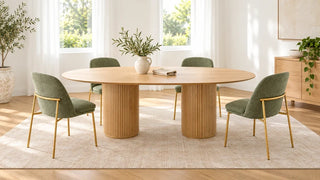 Light wood oval dining table on two fluted pedestal bases with sage dining chairs.