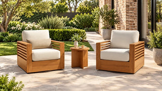 Beatriz wood slatted outdoor chairs and a round table on a stone patio beside a garden.