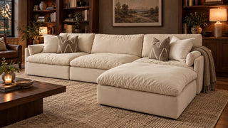 Cream sectional with a right chaise in a softly lit room with walnut bookshelves.