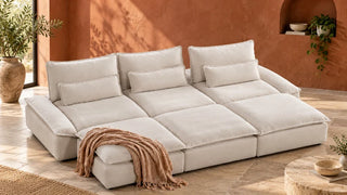 A cream Ace sofa with deep seats and three ottomans in a room with a terracotta wall