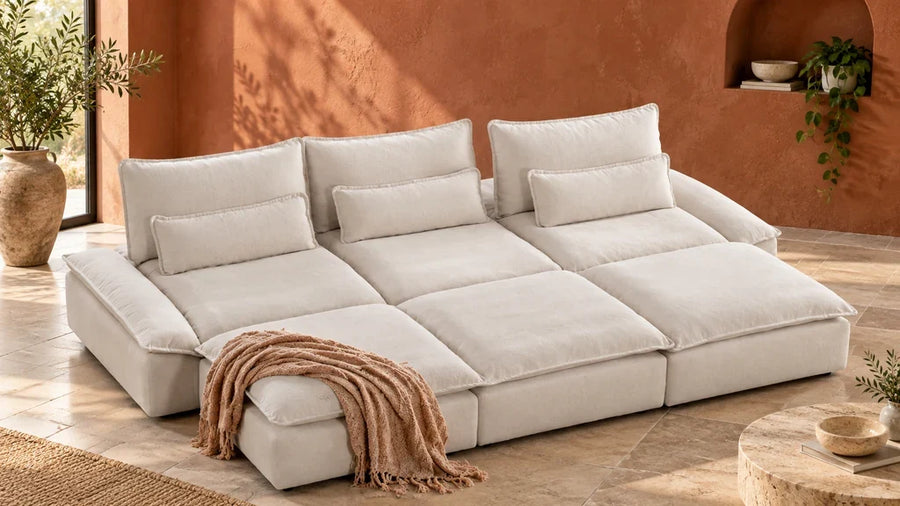 A cream Ace sofa with deep seats and three ottomans in a room with a terracotta wall