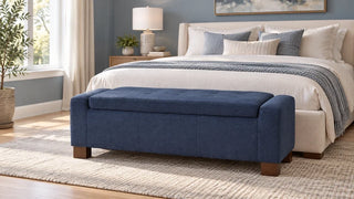 A blue upholstered bench centered at the foot of a cream bed