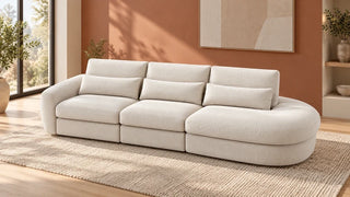 Cream curved sectional with a rounded chaise on the right in a room with a terracotta wall.