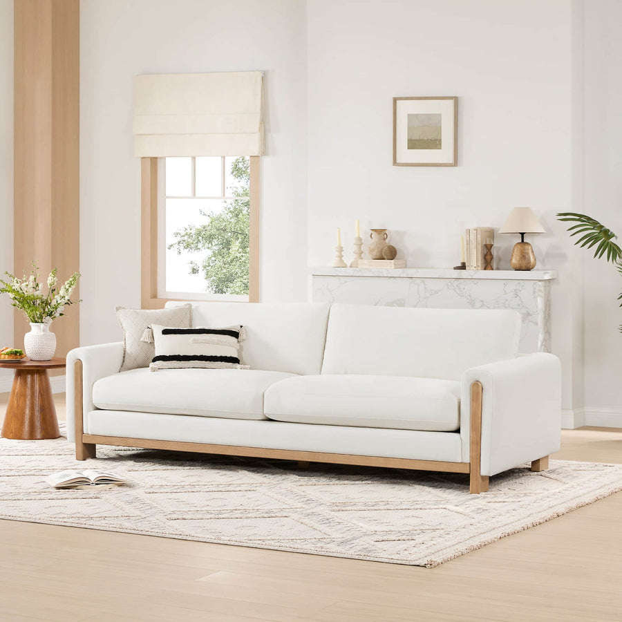 Keaton sofa in Ivory with a light wood base, white walls and a pale patterned rug.