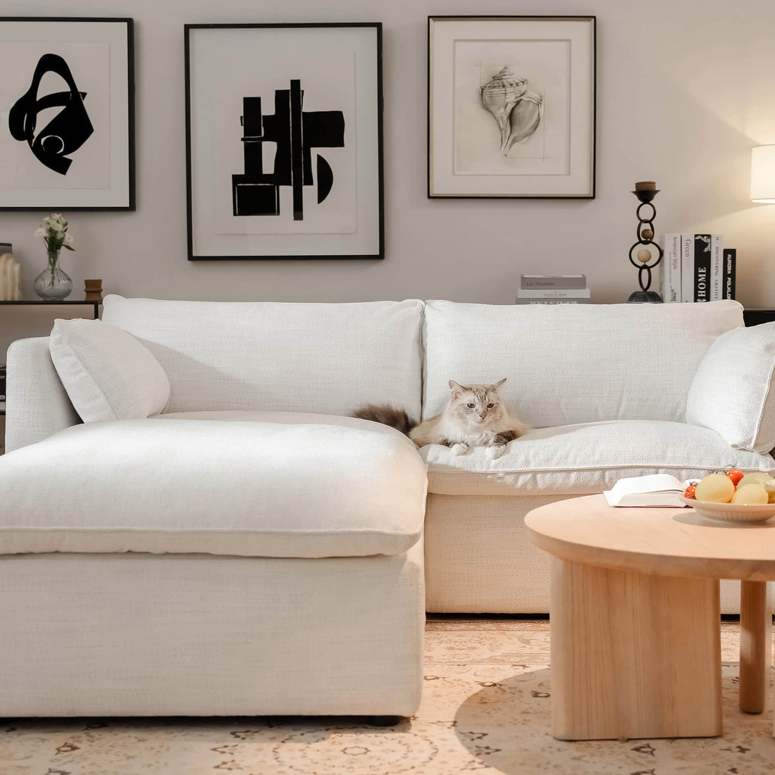 A cozy living room with a white sectional sofa, a wooden coffee table, and a cat lounging on the couch.