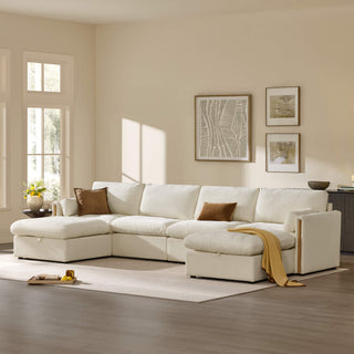 White modular sectional sofa with two chaise extensions, brown accent pillows, and a mustard throw, styled in a sunlit living room with framed artwork, a flower arrangement, and a neutral area rug.