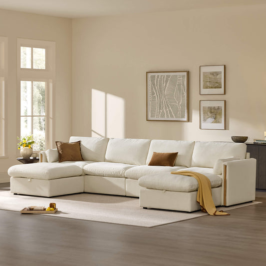 White modular sectional sofa with two chaise extensions, brown accent pillows, and a mustard throw, styled in a sunlit living room with framed artwork, a flower arrangement, and a neutral area rug.