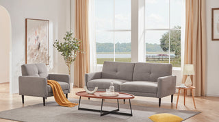 Gray sofa and matching armchair arrange an open-plan living room seating zone with large windows, coffee table, soft rug, and bright natural light for sofa layout inspiration
