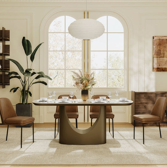 Modern marble dining table with a sculptural bronze base and tan leather chairs under a paper pendant.