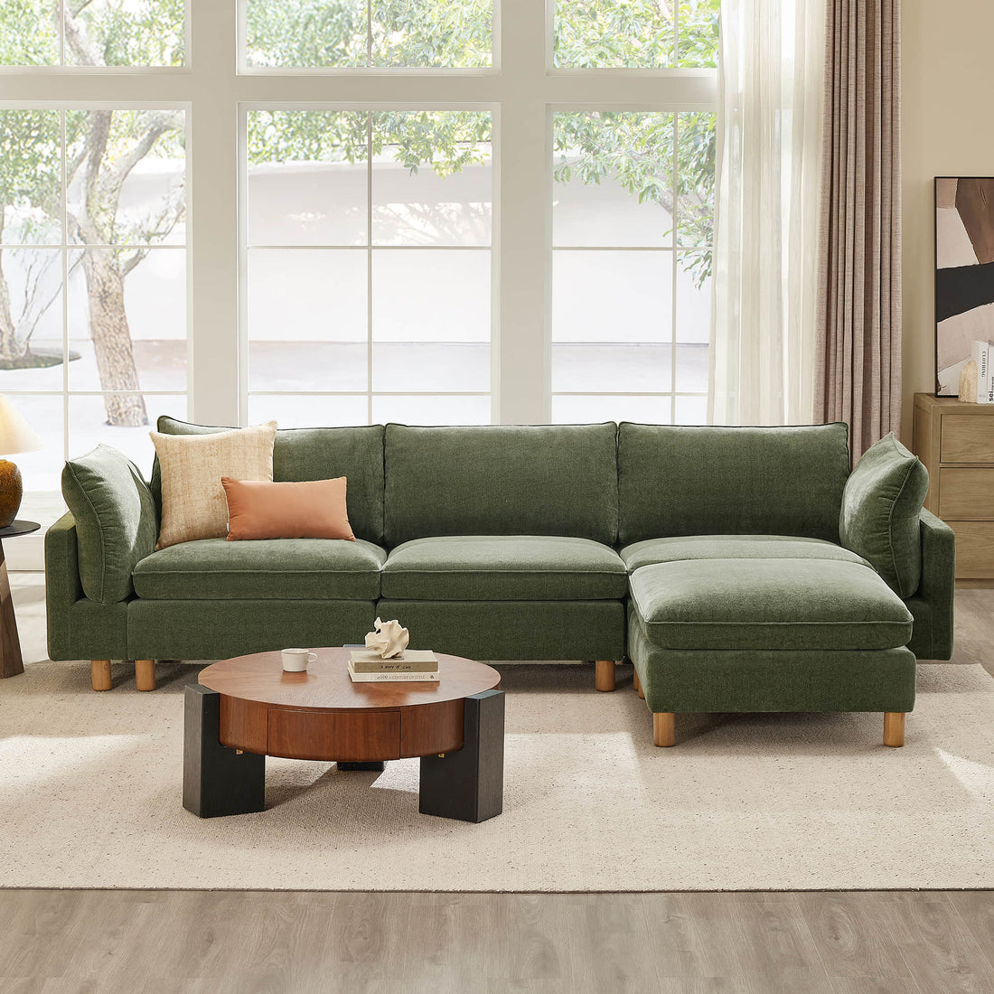 Green sectional sofa with wooden legs in a bright living room with large windows.