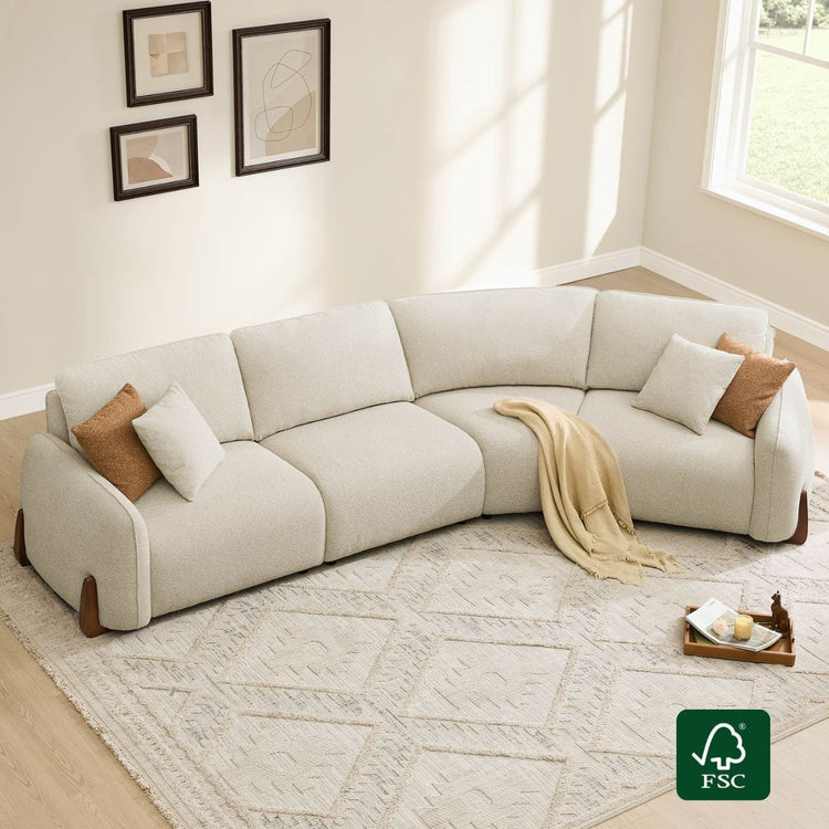 Cream modular 4-seat curved sofa with wood legs, shown in a living room setting with decor.