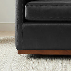 Close-up of Henry Modern Swivel Accent Chair's black leather cushion and wooden base - CHITA Living