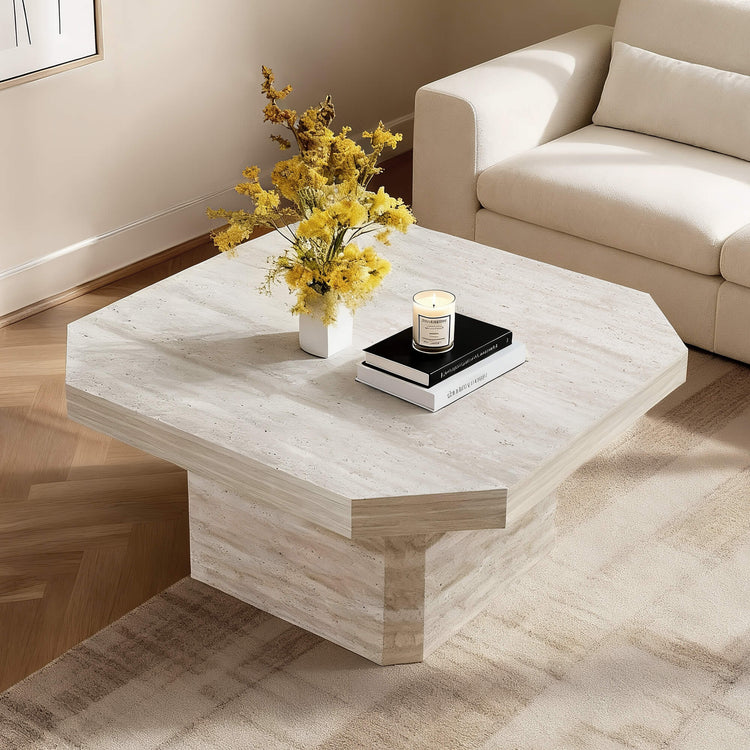 Midcentury octagon travertine coffee table with a vase of yellow flowers, a candle, and books.
