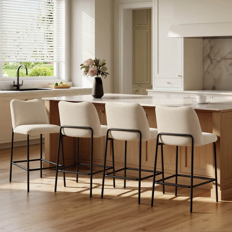 Set of cream upholstered barstools with black metal bases beside a kitchen island