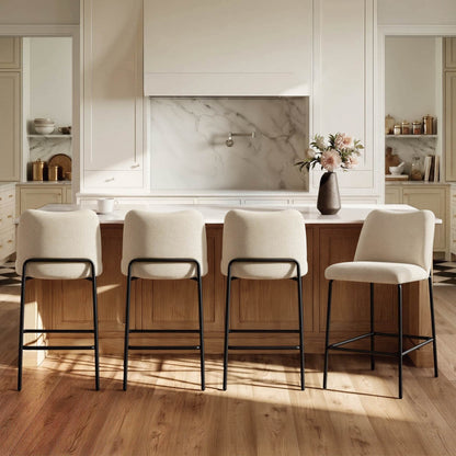 Four cream upholstered barstools with black metal bases in a modern kitchen