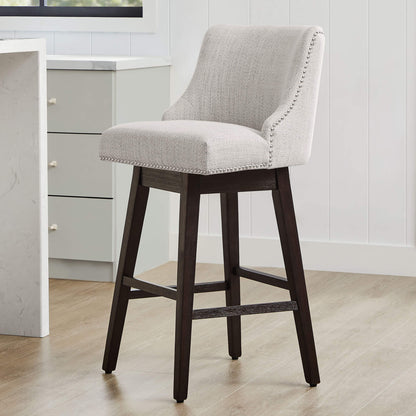 Light gray Asher swivel bar stool with nailhead trim and sturdy wooden legs in modern kitchen - CHITA Living