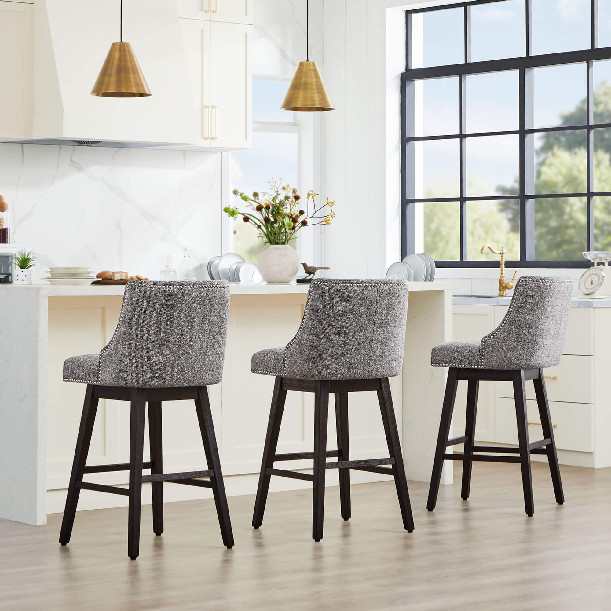 Asher swivel bar stools in gray upholstery with nailhead trim at a modern kitchen island - CHITA Living