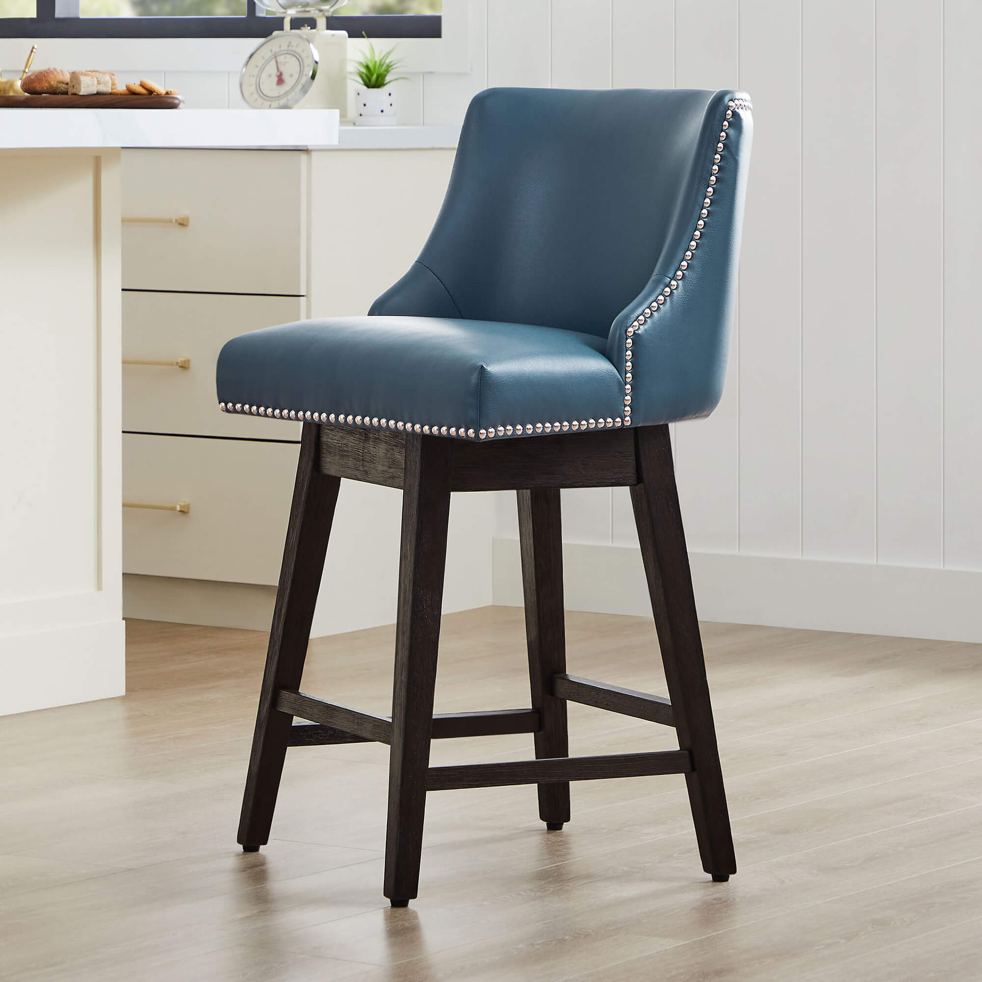 Teal Asher swivel bar stool with nailhead trim and solid wooden legs in modern kitchen - CHITA Living