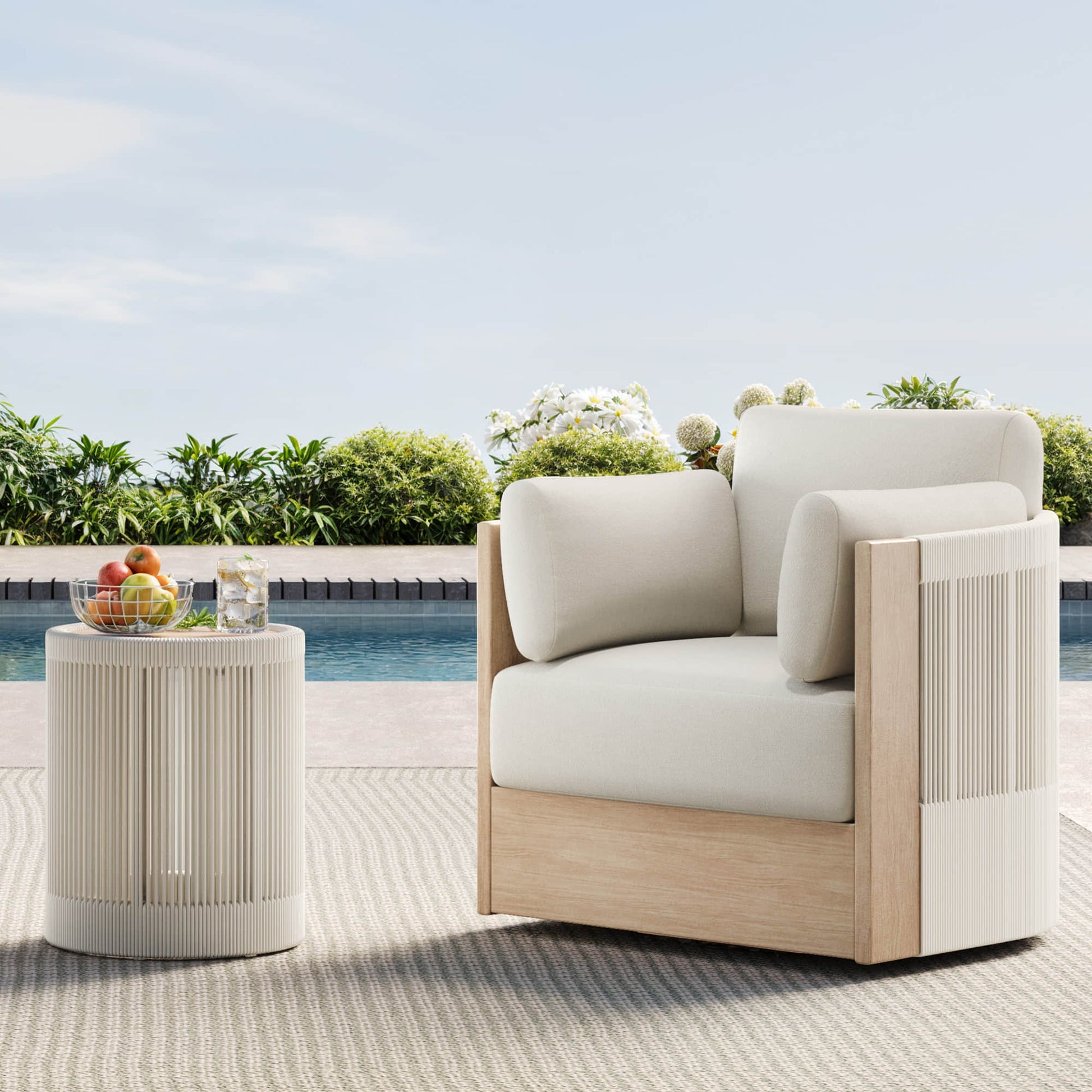 Clover Acacia Wood Woven Outdoor Bistro Set with Swivel Chair, poolside with a side table and fruit.