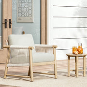 A Sienna Modern Acacia wood woven outdoor lounge chair with a cushion, next to a side table with orange juice.