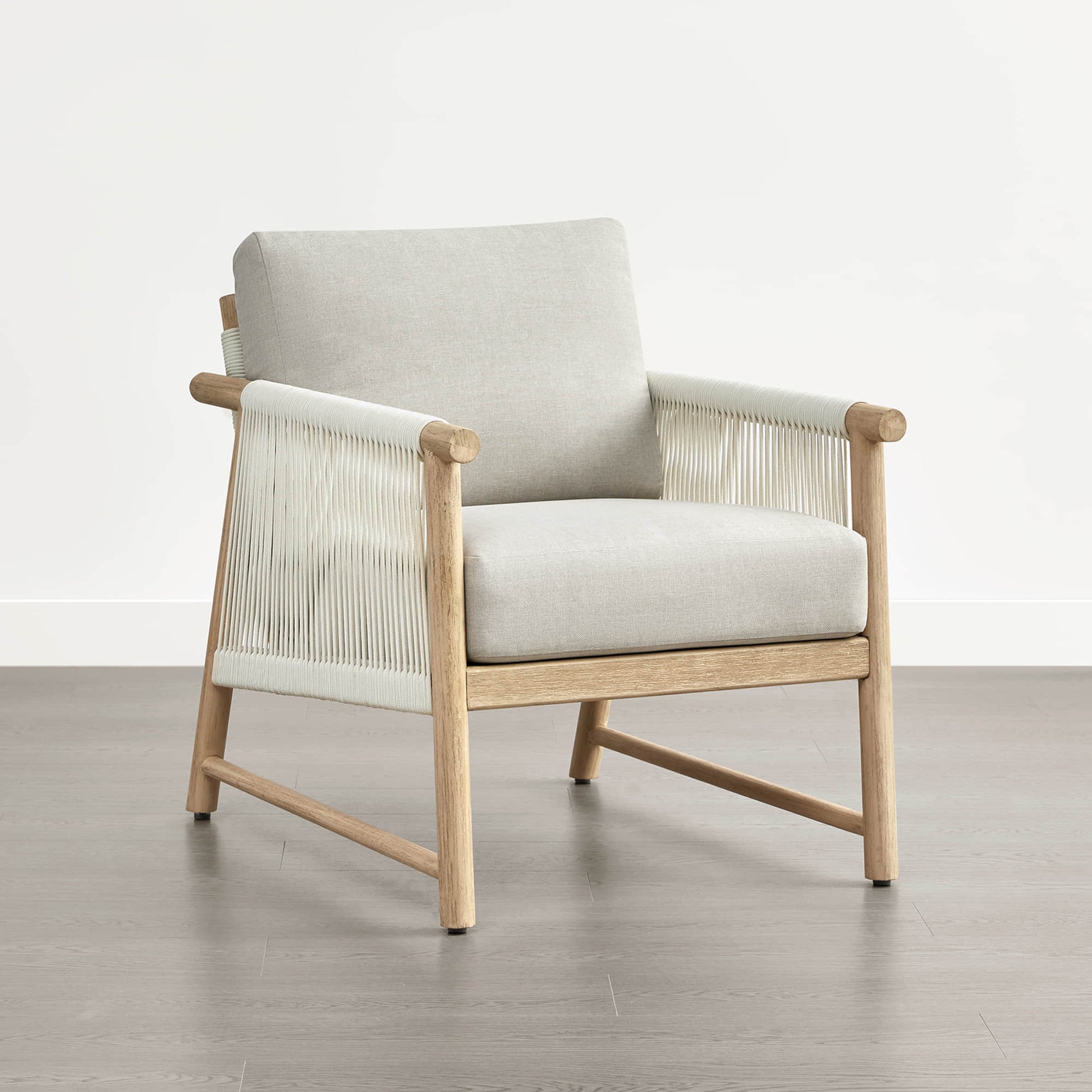 A Sienna Modern Acacia Wood Woven Outdoor Bistro Set chair with light beige cushions on a wooden floor.
